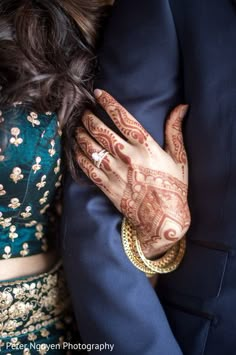 the bride and groom are holding hands with henna tattoos on their arms, both wearing matching rings