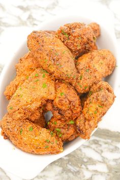 a white bowl filled with fried food on top of a marble countertop next to a knife