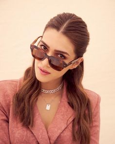 a woman with sunglasses on her head wearing a pink shirt and silver chain around her neck