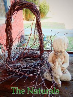 a teddy bear sitting on top of a wooden table next to a basket filled with twigs