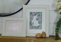 two framed pictures sitting next to each other on a shelf with flowers and eggs in front of them