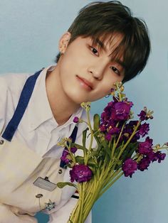 a young man holding a bunch of purple flowers