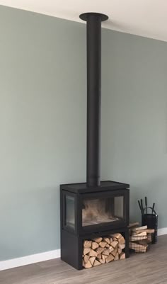 a wood burning stove in a living room next to stacks of firewood on the floor