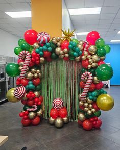 the balloon arch is decorated with candy canes and christmas decorations in red, green, and gold colors