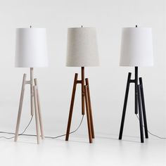 three wooden lamps with white shades on them and one light turned on the other side