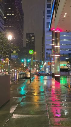 an empty city street at night with rain falling on the ground and buildings in the background