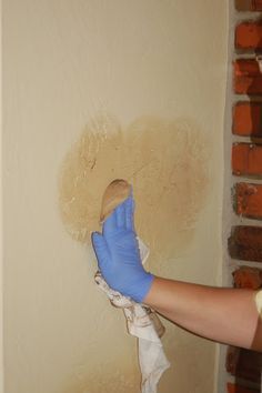 a person in blue gloves is painting a wall