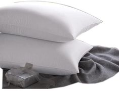 two pillows and a gift wrapped in a gray blanket on top of a white pillow