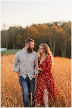 a man and woman walking through tall grass