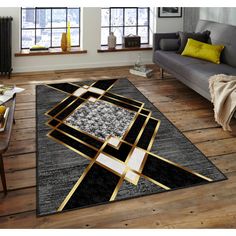 a living room area rug with black and gold geometric designs on the floor, in front of a gray couch