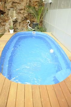 an above ground pool with wooden decking and blue water in the middle, surrounded by rocks