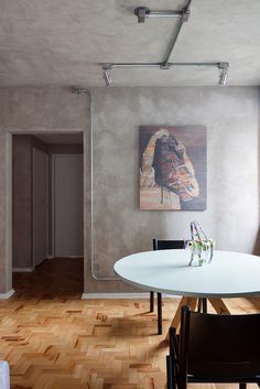 a white table and chairs in a room with wood flooring on one side and a painting on the other