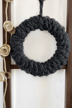 a yarn wreath is hanging on the wall next to a wooden frame with flowers in it