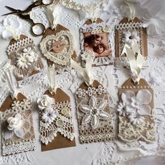 there are many tags on the table with lace and flowers attached to them, all decorated in different shapes and sizes