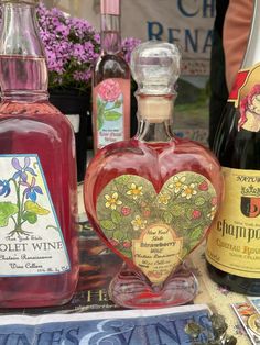 several bottles of wine are sitting on a table next to each other, including one with a heart shaped bottle