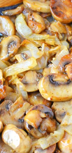 cooked mushrooms and onions in a skillet with wooden spoons on the side, ready to be eaten