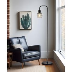 a living room with a chair, lamp and pictures hanging on the wall above it