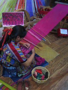 a woman sitting on the floor working on some material