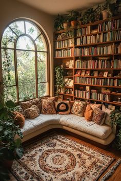 a corner couch in front of a large window with bookshelves and plants on it