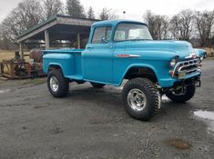 an old blue pickup truck parked in front of a building