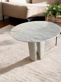 a white marble coffee table sitting on top of a rug in front of a couch