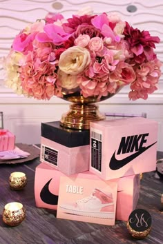 a vase filled with pink flowers sitting on top of a table next to some boxes