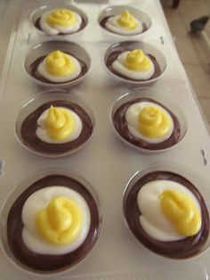 chocolate cupcakes with yellow icing and eggs on top in a muffin tin