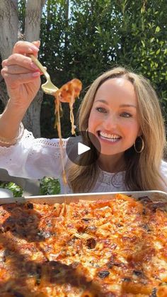 a woman holding up a slice of pizza