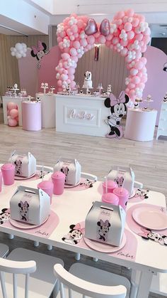 a table set up for a minnie mouse birthday party with pink and white balloons in the background