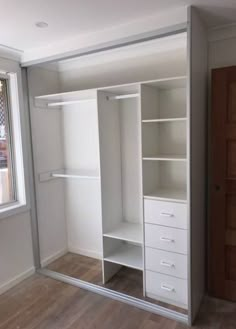 an empty closet with white shelves and drawers