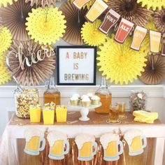 a baby is brewing themed party with beer and paper fan decorations on the wall behind it