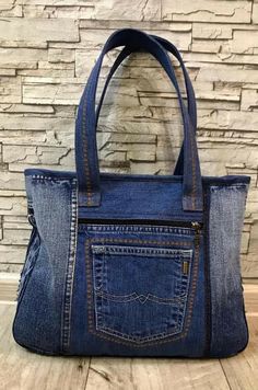 a denim handbag is shown against a brick wall