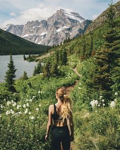 a woman walking down a trail in the mountains