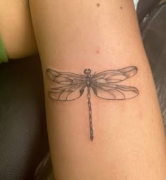 a small dragonfly tattoo on the arm