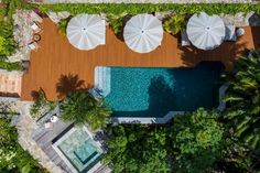 an aerial view of a pool surrounded by trees and lawn chairs with umbrellas over it