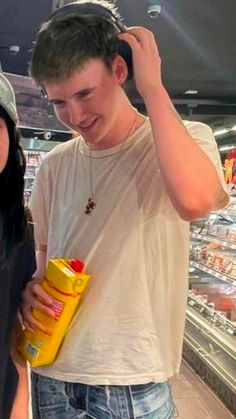 a young man and woman standing next to each other in a grocery store looking at food