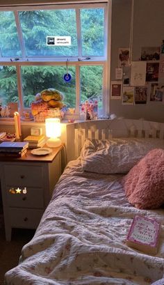 a bedroom with a bed, desk and window in the corner is lit by a candle