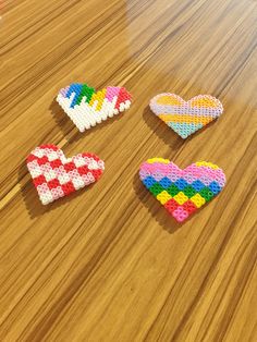 three heart shaped beads sitting on top of a wooden table