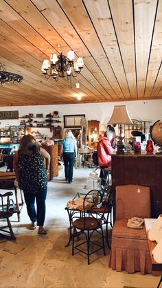 people are shopping in an antique store with wooden ceilinging and chandeliers hanging from the ceiling