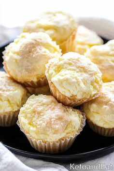 a black plate topped with muffins on top of a white table cloth next to a cupcake tin