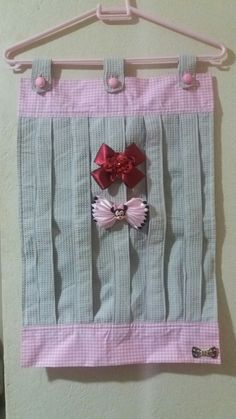 a pink and grey wall hanging with two bows on it's side, attached to a white hanger