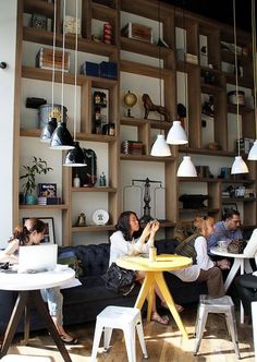 people are sitting around a table in a room with shelves on the wall behind them