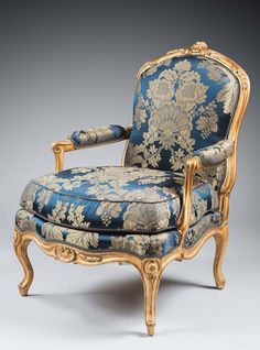 an ornately decorated chair with blue and gold fabric on the back, against a white background