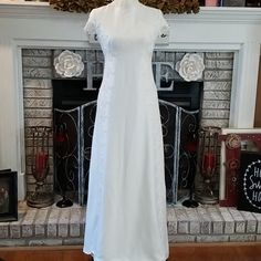 a white dress on display in front of a fireplace