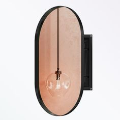 a round mirror hanging from the side of a wall with a light bulb on it