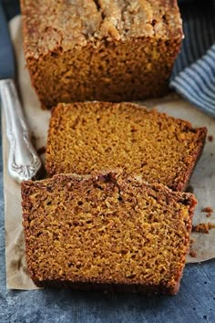 sliced loaf of pumpkin bread sitting on top of a piece of parchment paper next to a fork