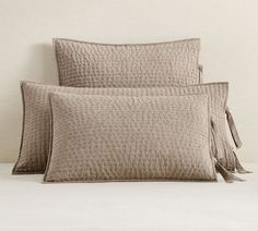 two pillows with tassels on them sit next to each other in front of a white wall