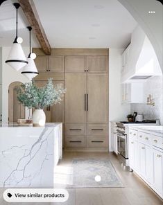 a large kitchen with white cabinets and marble counter tops, along with an archway leading to the dining room