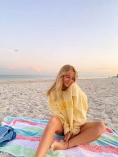 a woman sitting on top of a blanket on the beach