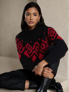 a woman is sitting on the floor wearing a black and red sweater